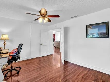 a view of a workspace with wooden floor and a ceiling fan