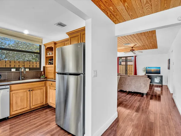 a kitchen with stainless steel appliances granite countertop a refrigerator a sink and a stove with wooden floor