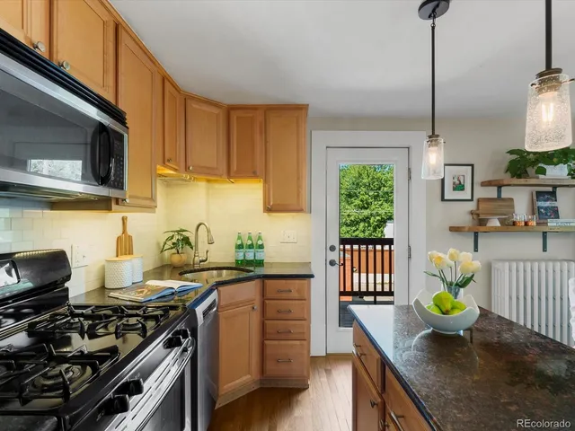 a kitchen with stainless steel appliances a stove a sink a microwave a dining table and chairs with wooden floor