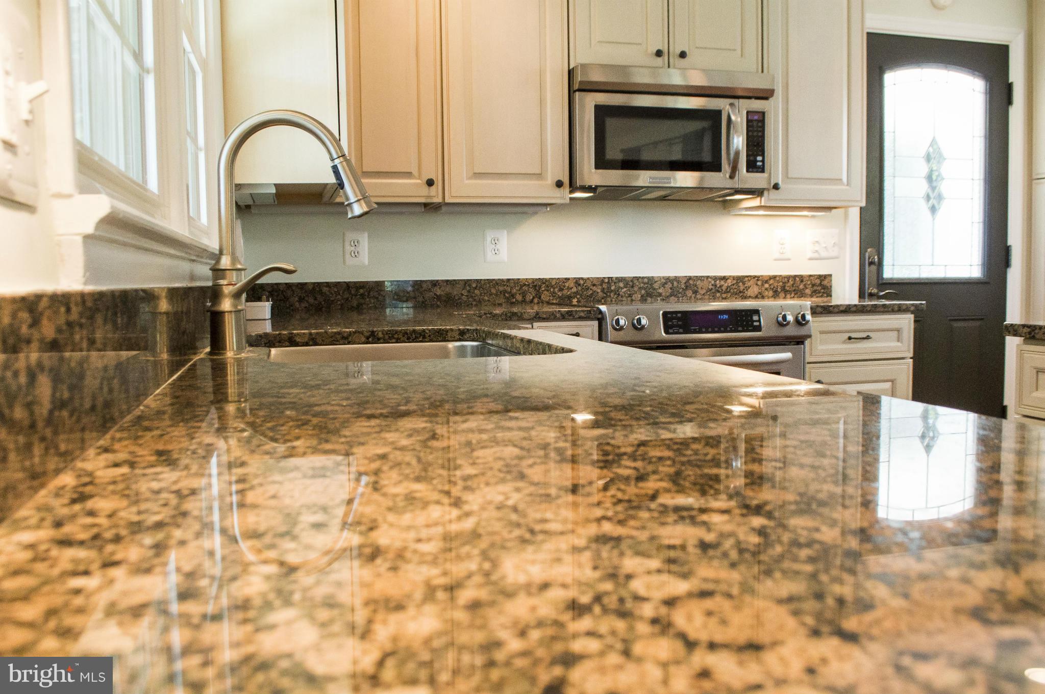 2050 Holland Cliffs Road Huntingtown, MD 20639 - Photo 11 of 29 a kitchen with granite countertop a stove a sink and a microwave