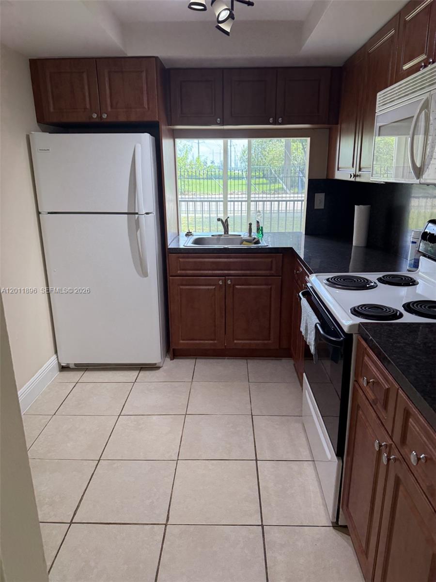 9411 Southwest 4th Street, Unit 111 Miami, FL 33174 - Photo 6 of 20 a kitchen with a stove a refrigerator and a microwave