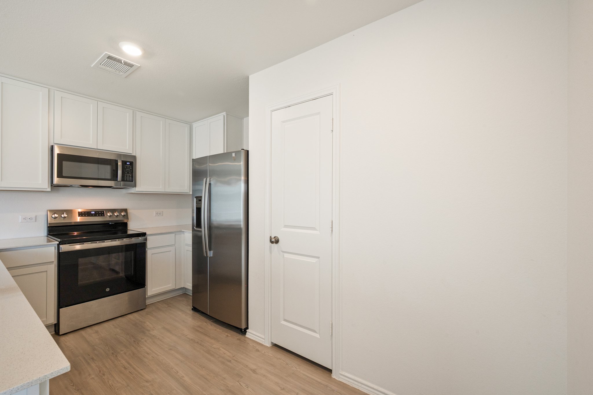 412 Heritage Grvs Road Bertram, TX 78605 - Photo 12 of 15 Modern kitchen featuring light wood-finish flooring, white cabinetry, light-toned countertops, and stainless steel appliances