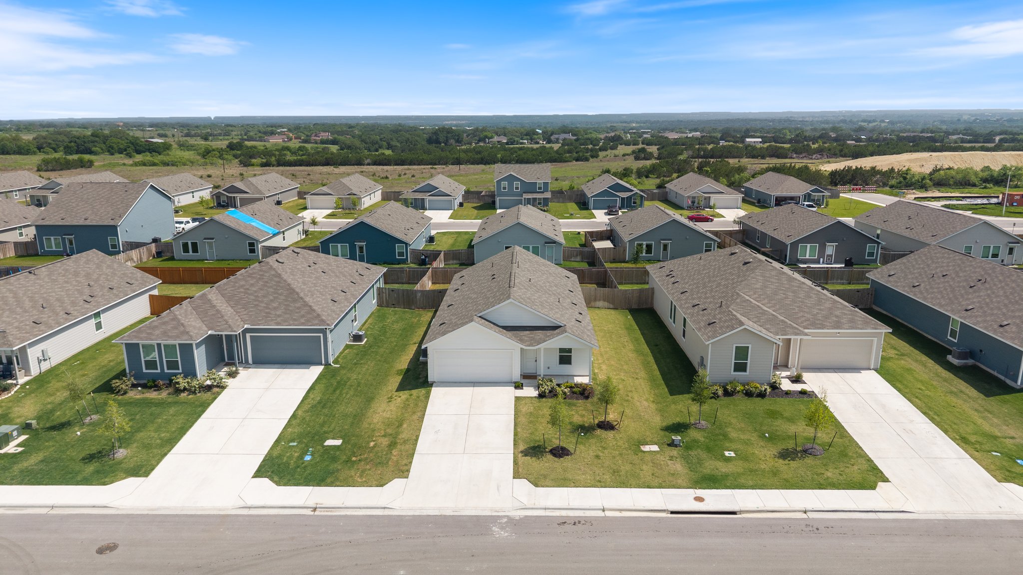 412 Heritage Grvs Road Bertram, TX 78605 - Photo 14 of 15 Residential community featuring single-story homes with attached garages, concrete driveways, and landscaped front yards