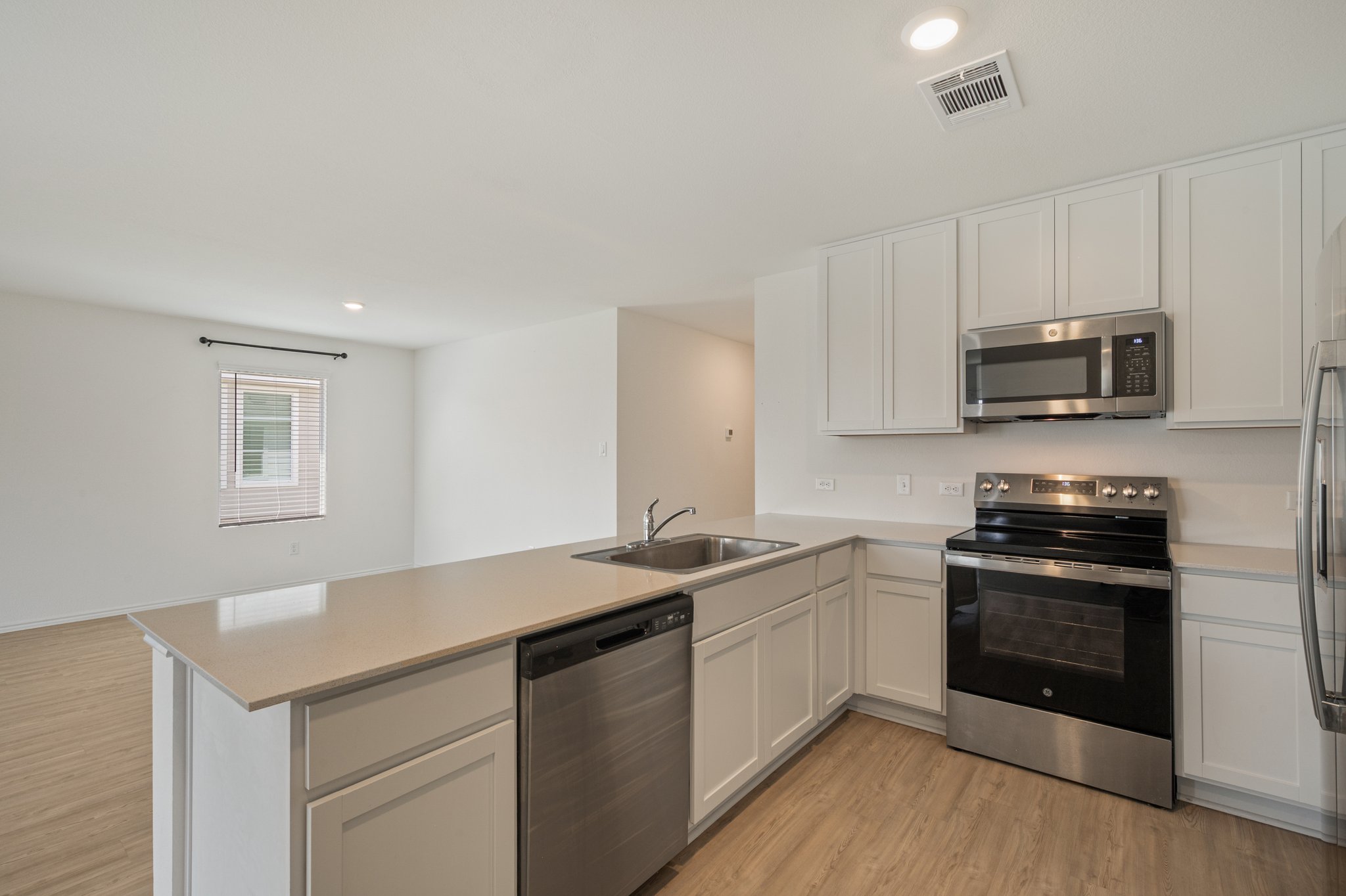 412 Heritage Grvs Road Bertram, TX 78605 - Photo 10 of 15 Kitchen featuring white cabinetry, light-toned countertops, a stainless steel sink, and stainless steel appliances including a range, dishwasher, and microwave