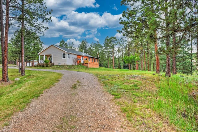 a view of house in front of a big yard with large trees