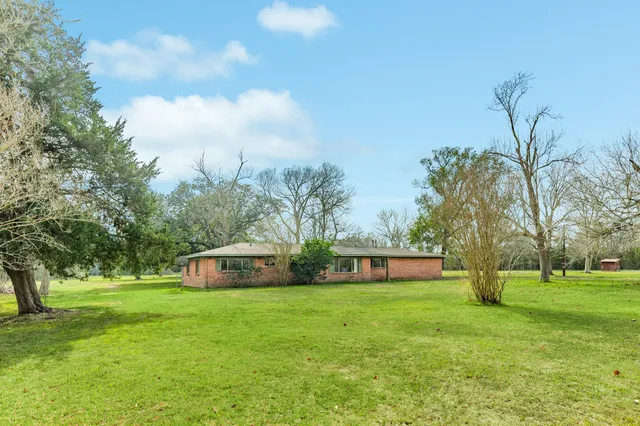 a front view of a house with garden and trees