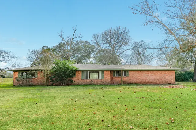 a view of front of house with yard and trees in the background
