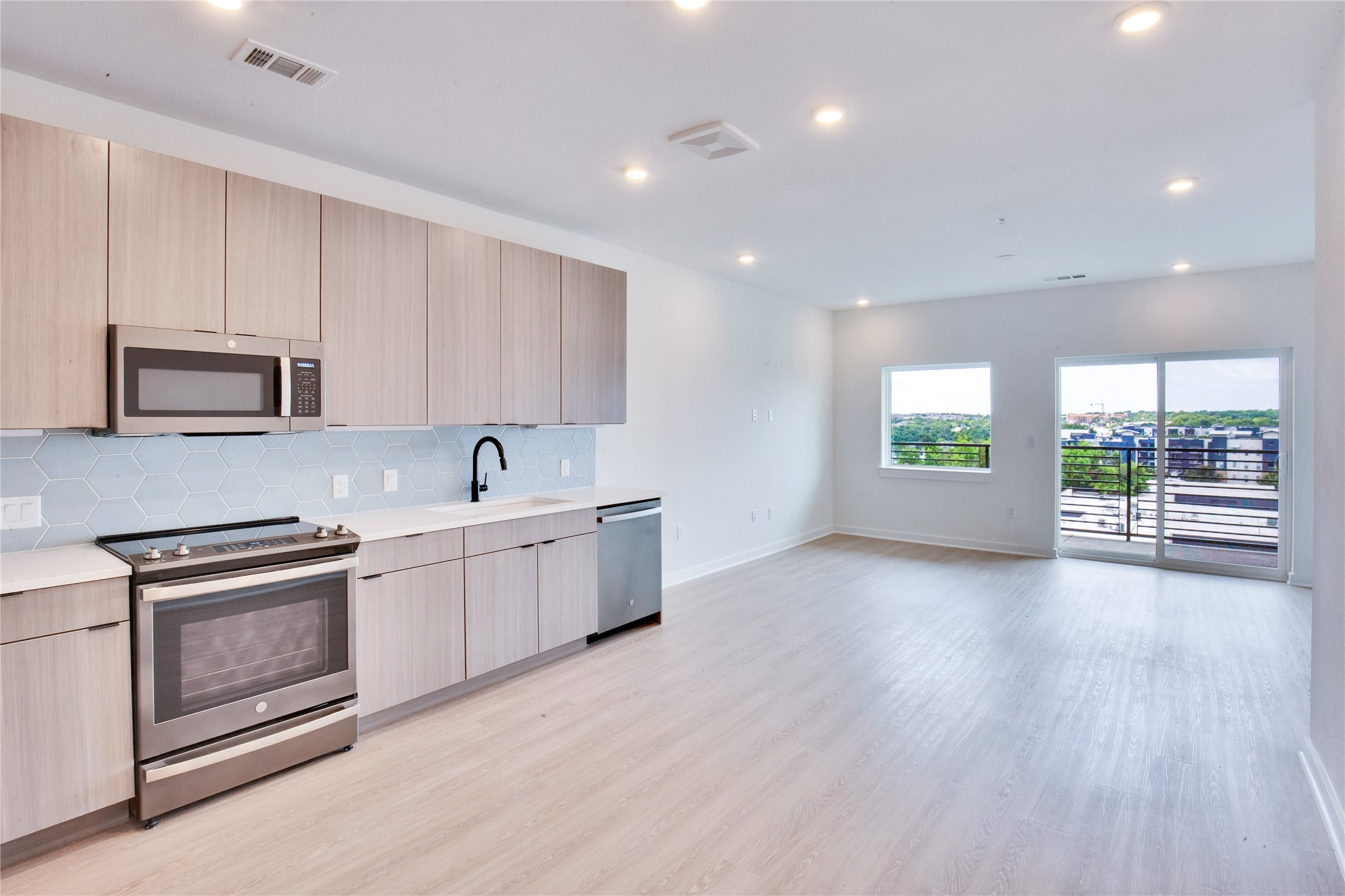 4802 South Congress Avenue, Unit 407 Austin, TX 78745 - Photo 5 of 25 a large kitchen with stainless steel appliances granite countertop a stove a sink white cabinets and a wooden floors