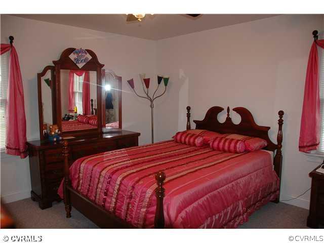 17363 Parsons Ridge Road Beaverdam, VA 23015 - Photo 7 of 12 a bedroom with a bed a mirror on dresser and a chandelier