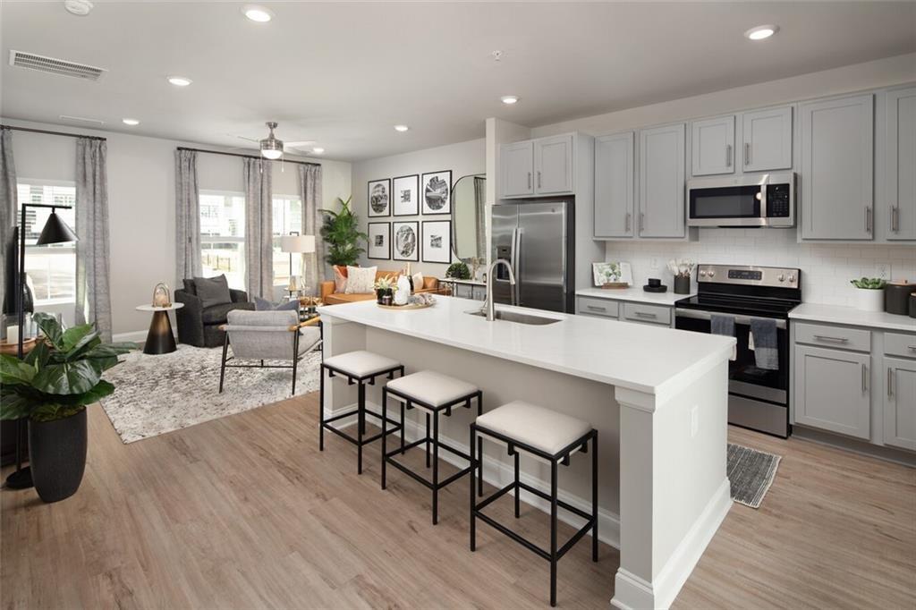 3960 Redan Road, Unit B2 Stone Mountain, GA 30083 - Photo 8 of 23 a kitchen with stainless steel appliances a dining table chairs microwave and sink