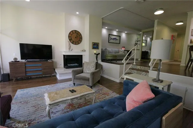 a living room with furniture a wooden floor and a large mirror