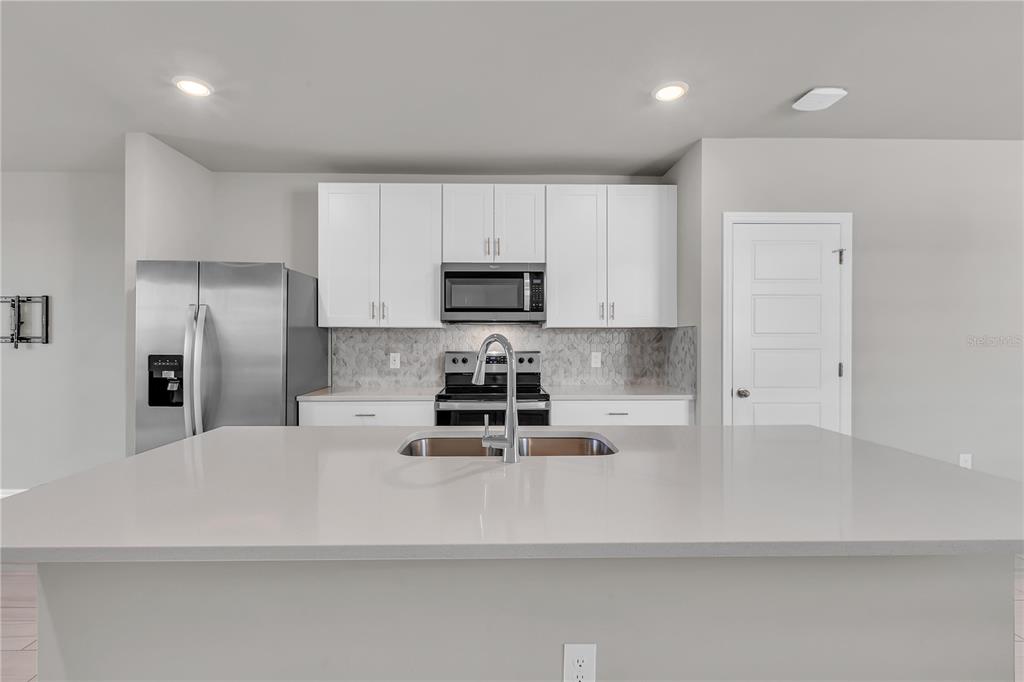 44254 Frontier Drive Punta Gorda, FL 33982 - Photo 13 of 48 a kitchen with stainless steel appliances a refrigerator a sink a stove a microwave and white cabinets