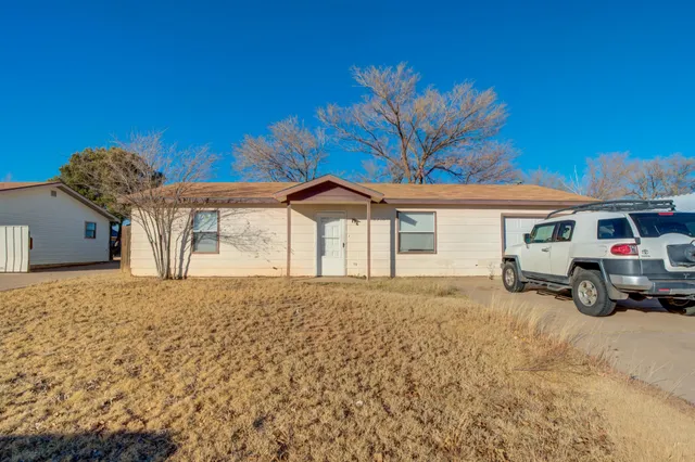 a view of a house with a large space and a car parked in front of it