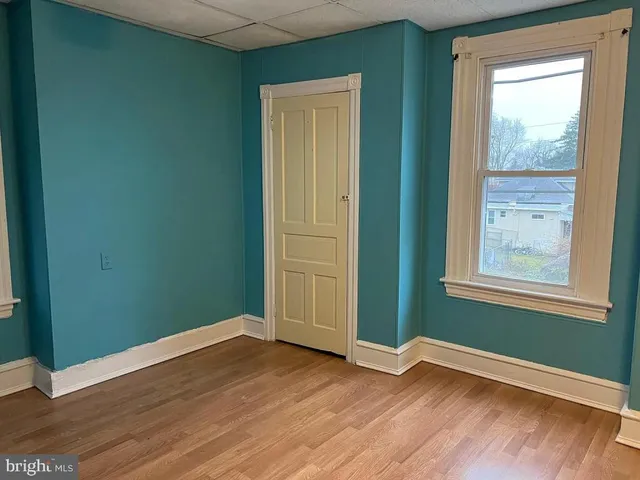 an empty room with wooden floor closet and windows