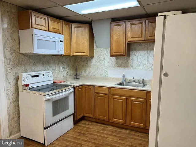 a kitchen with stainless steel appliances granite countertop a stove a sink and a refrigerator with wooden cabinets