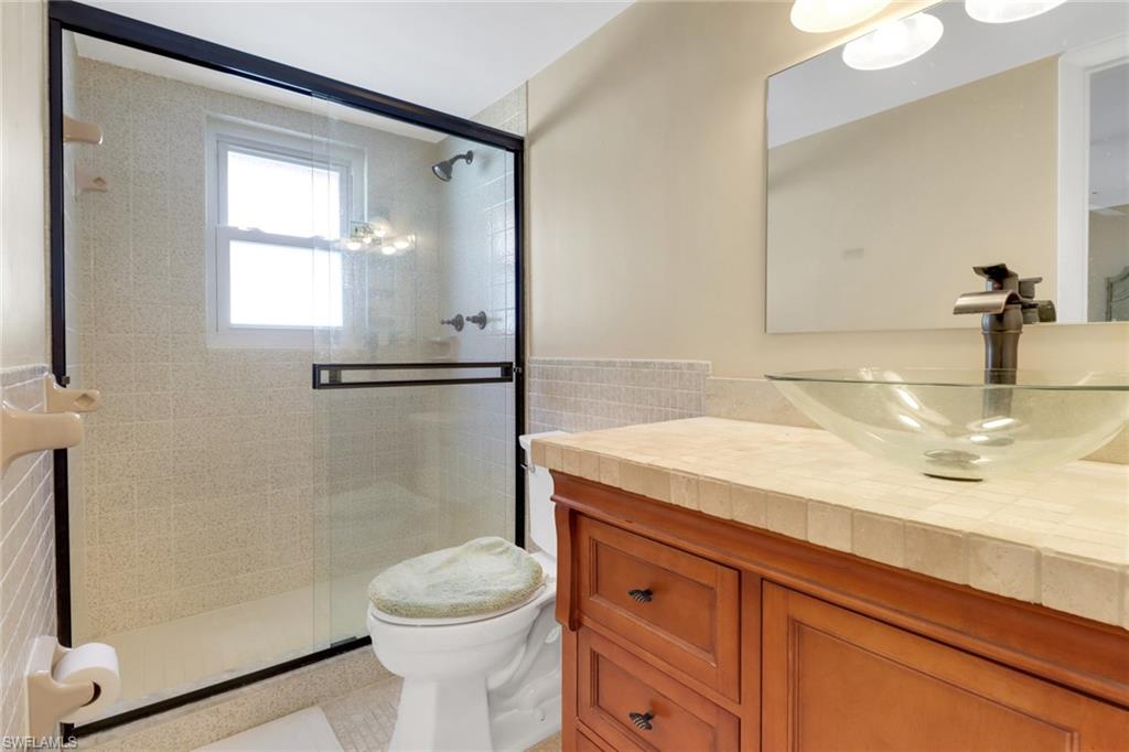 1155 Sandpiper Street, Unit D4 Naples, FL 34102 - Photo 15 of 39 Bathroom featuring tile walls, vanity, and a stall shower