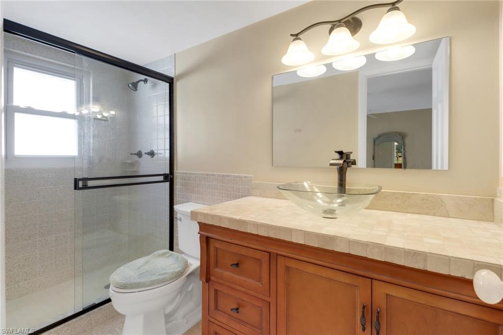 1155 Sandpiper Street, Unit D4 Naples, FL 34102 - Photo 33 of 39 Bathroom with vanity, a stall shower, and tile walls
