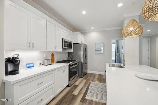 a kitchen with granite countertop a sink stainless steel appliances and white cabinets