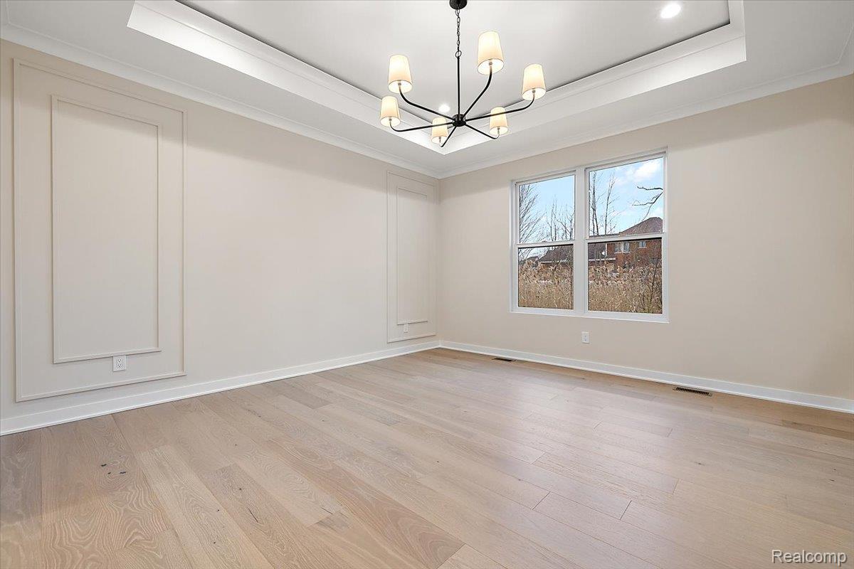 2044 Breckenridge Court Rochester, MI 48309 - Photo 17 of 33 Empty room with crown molding, a raised ceiling, light wood finished floors, and a chandelier
