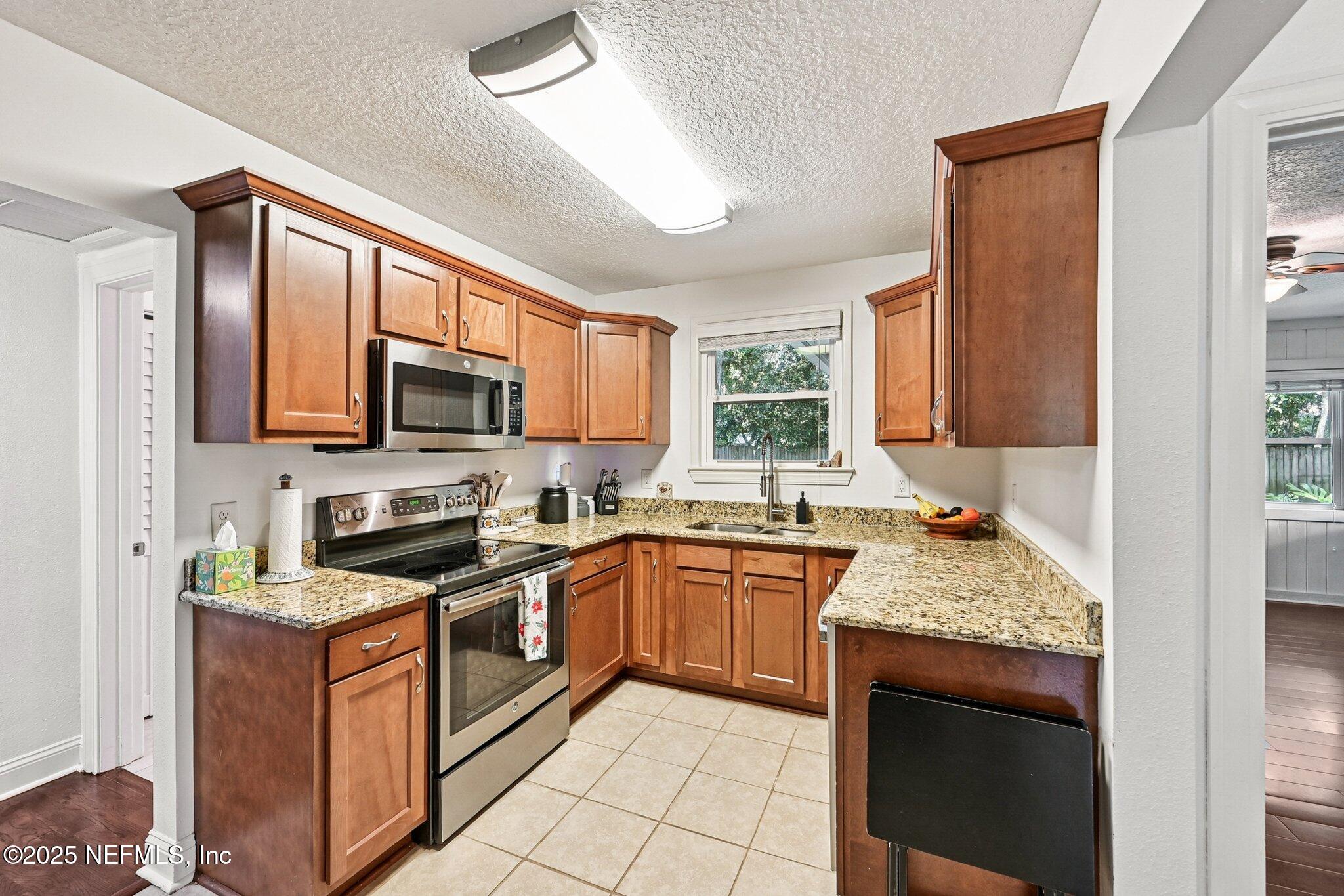 4637 Homestead Road Jacksonville, FL 32210 - Photo 15 of 43 a kitchen with stainless steel appliances granite countertop wooden cabinets a stove top oven a sink and dishwasher