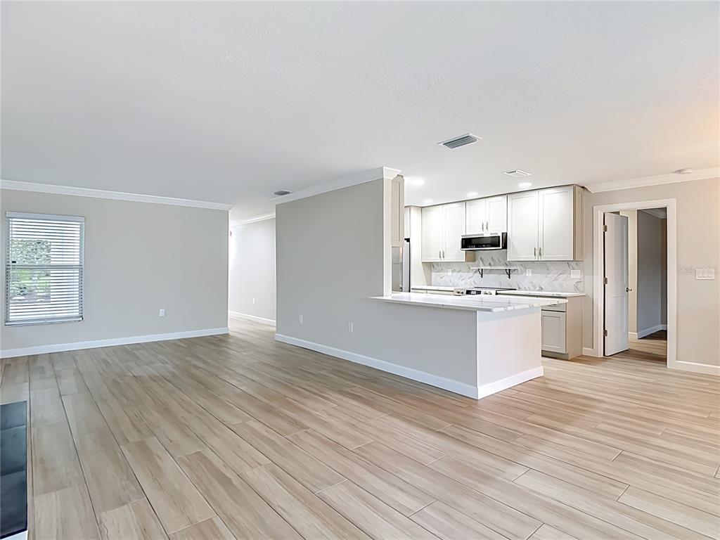 4536 Mitcher Road New Port Richey, FL 34652 - Photo 31 of 46 a large white kitchen with kitchen island a sink white cabinets and stainless steel appliances