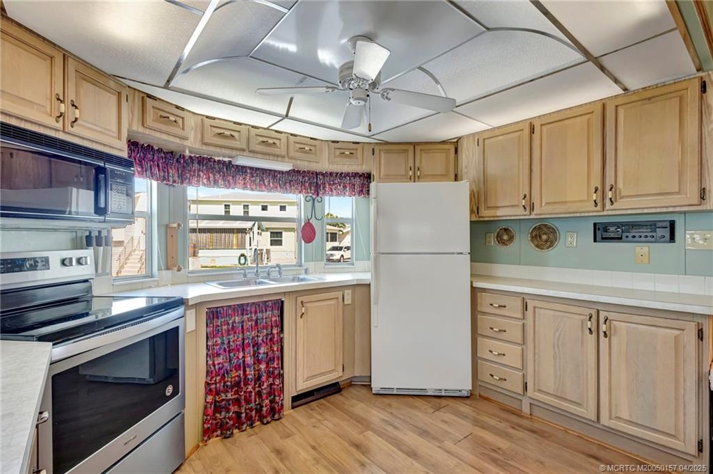 10725 South Ocean Drive, Unit 437 Jensen Beach, FL 34957 - Photo 11 of 32 a kitchen with stainless steel appliances granite countertop a refrigerator a stove a sink and white cabinets