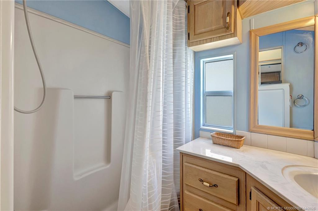 10725 South Ocean Drive, Unit 437 Jensen Beach, FL 34957 - Photo 17 of 32 a bathroom with a granite countertop sink and a mirror