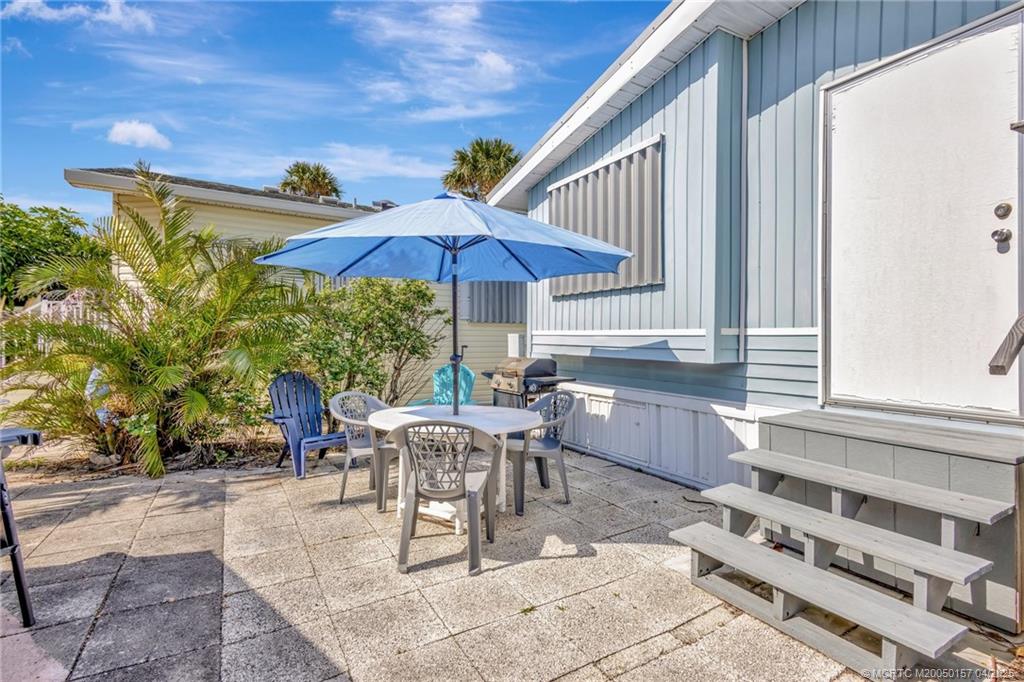 10725 South Ocean Drive, Unit 437 Jensen Beach, FL 34957 - Photo 22 of 32 a view of a patio with a dining table and chairs under an umbrella with a barbeque grill and couches