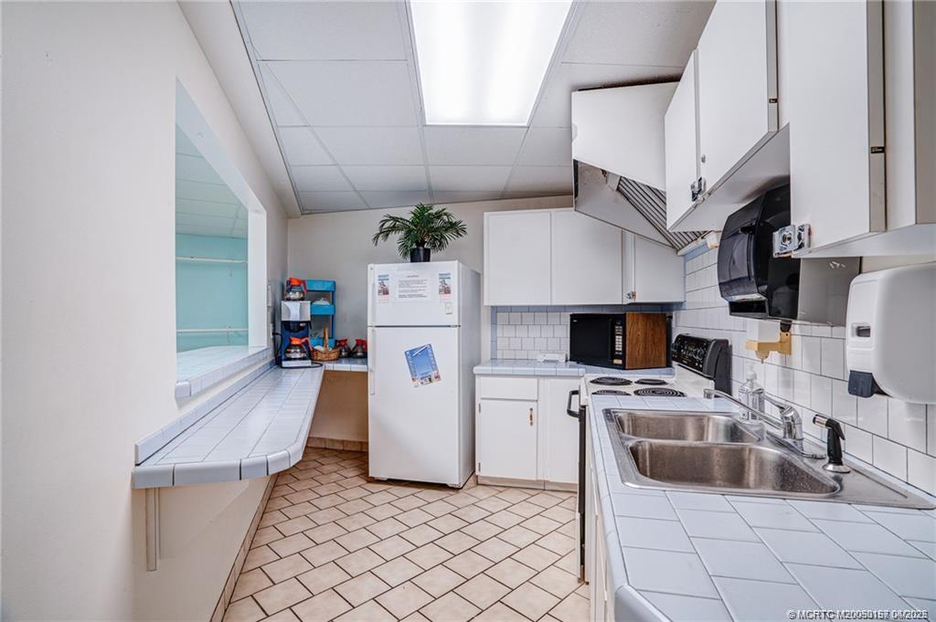 10725 South Ocean Drive, Unit 437 Jensen Beach, FL 34957 - Photo 24 of 32 a kitchen with stainless steel appliances a stove a refrigerator a sink a counter top space and cabinets