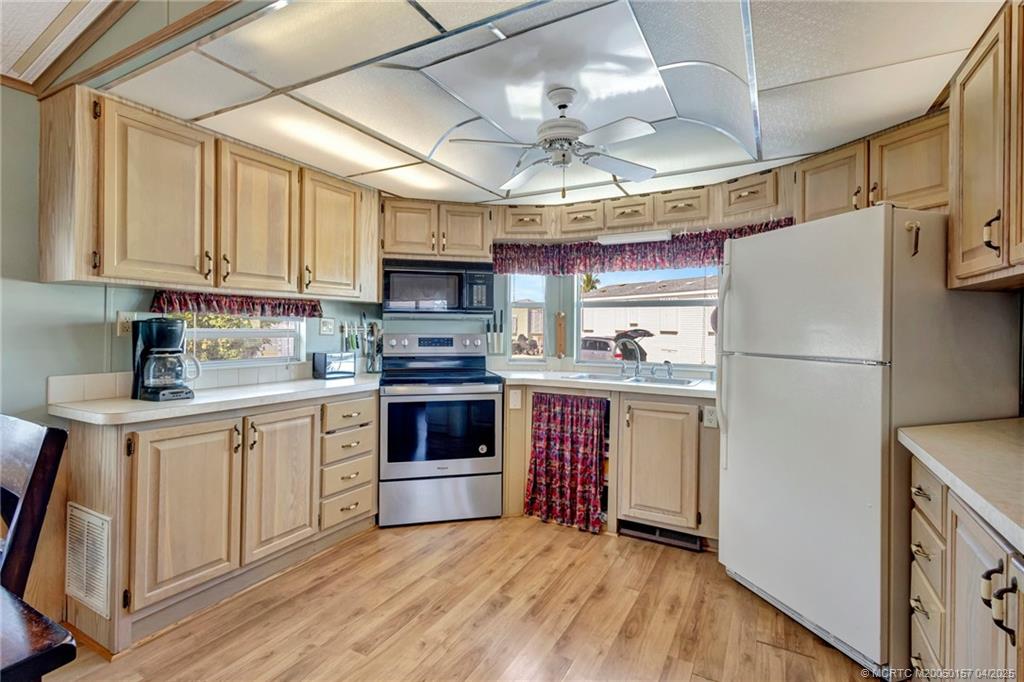 10725 South Ocean Drive, Unit 437 Jensen Beach, FL 34957 - Photo 10 of 32 a kitchen with stainless steel appliances granite countertop a refrigerator a stove a sink dishwasher and a refrigerator with wooden floor