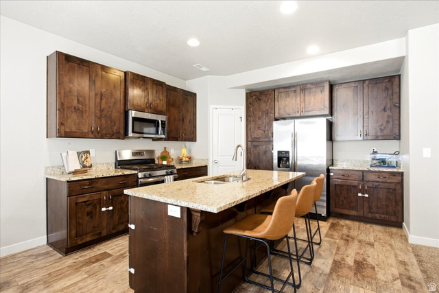 288 South 600 West Centerville, UT 84014 - Photo 6 of 27 Kitchen featuring wood-finish cabinetry, stainless steel appliances, a center island with sink, and granite countertops