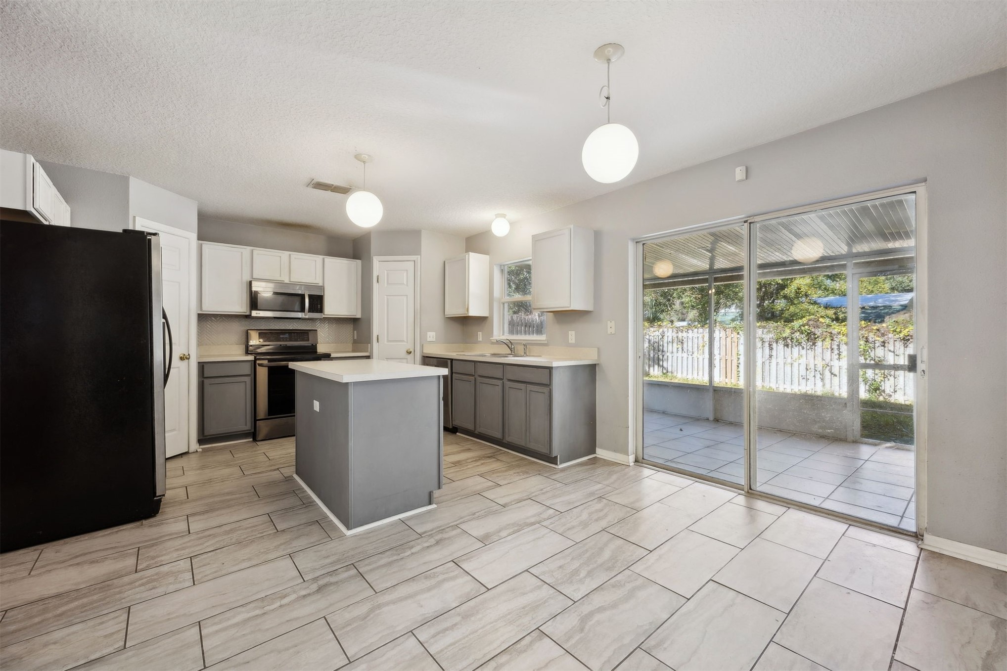87233 Kipling Drive Yulee, FL 32097 - Photo 11 of 38 a kitchen with stainless steel appliances kitchen island granite countertop a refrigerator a sink a stove a microwave and island