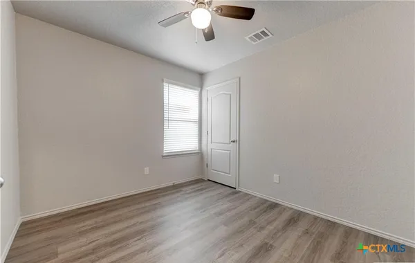 an empty room with a window and a chandelier fan