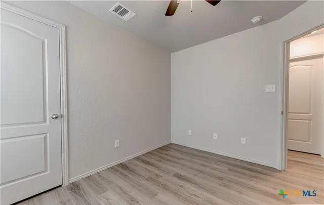 a view of an empty room with wooden floor and closet