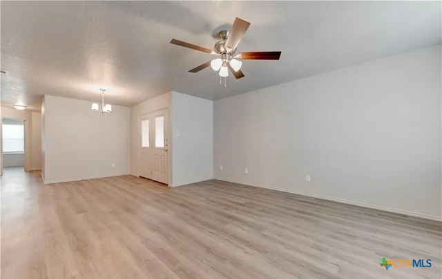 a view of an empty room with window and wooden floor