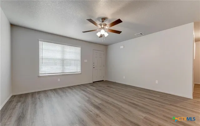 a view of an empty room with wooden floor and a window