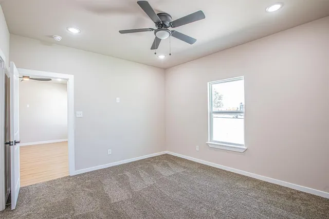 a view of an empty room and a ceiling fan and a window