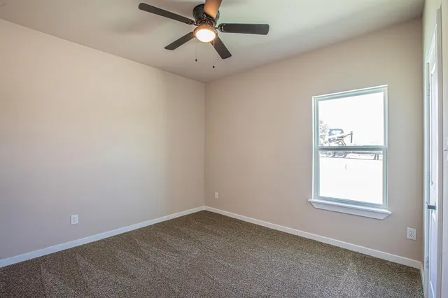 an empty room with a window and a fan