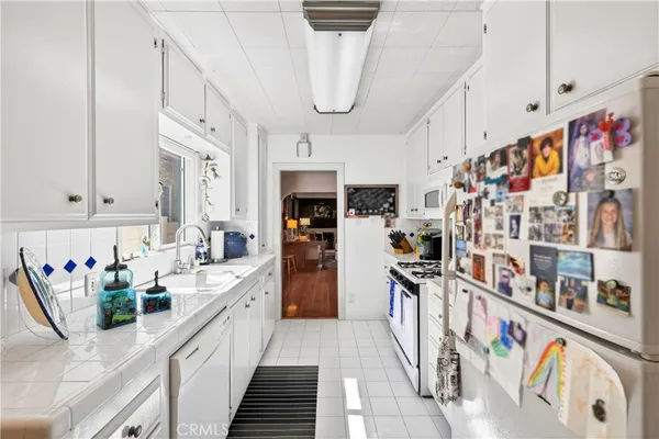 a kitchen with stainless steel appliances granite countertop a refrigerator and a white cabinets
