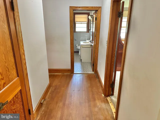 a view of a hallway with wooden floor and a bathroom