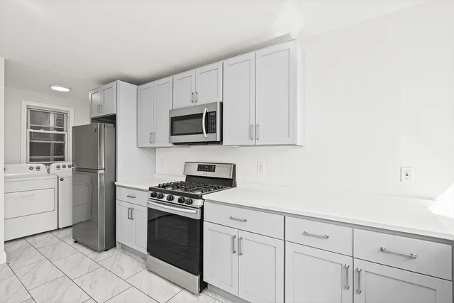 a kitchen with white cabinets and stainless steel appliances