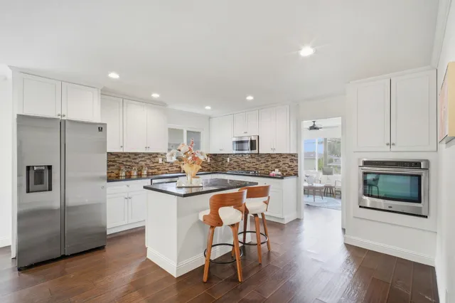 a kitchen with kitchen island granite countertop wooden cabinets and stainless steel appliances