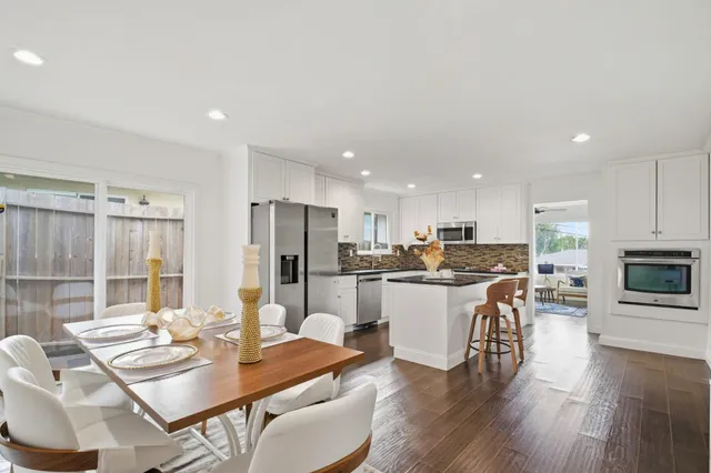 a kitchen with a dining table chairs wooden floor appliances and living room