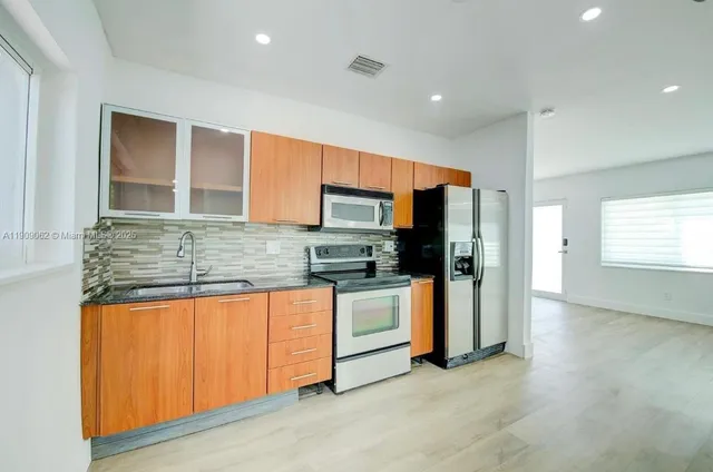 a kitchen with stainless steel appliances granite countertop a refrigerator and a stove top oven