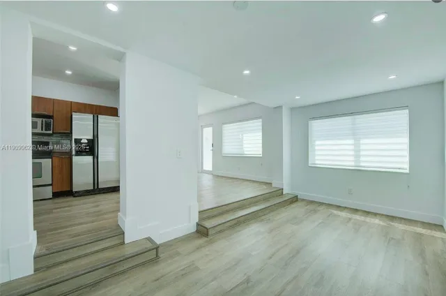 an empty room with wooden floor and a kitchen