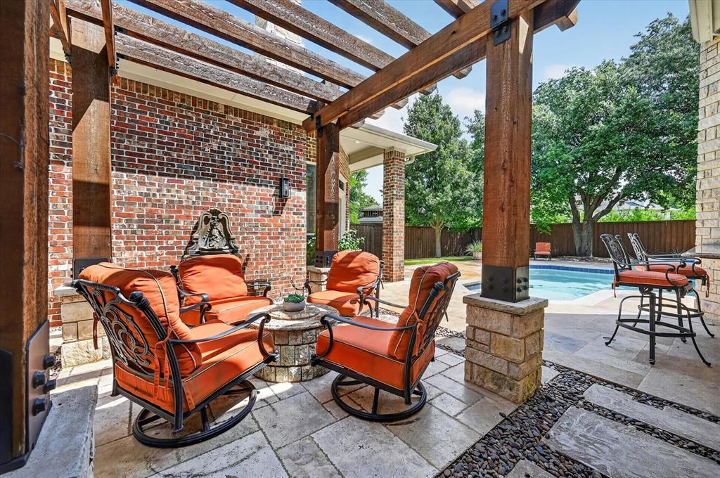 6416 Riverside Drive Plano, TX 75024 - Photo 26 of 35 Covered patio featuring a solid wood pergola with stone-clad pillars, paver stone flooring, and a built-in outdoor bar area, overlooking a swimming pool