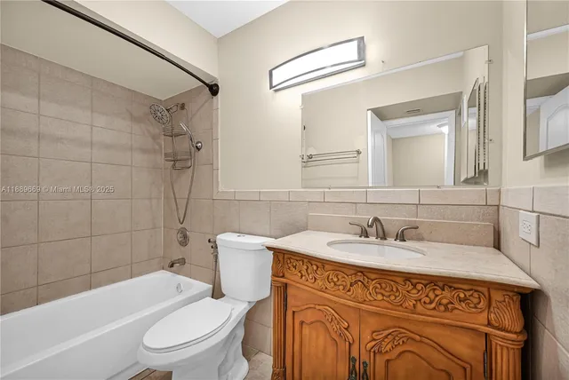 a bathroom with a sink a toilet a mirror a vanity and bathtub