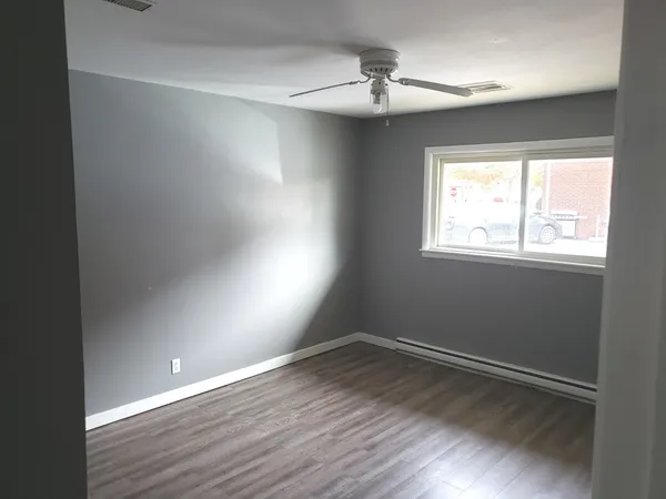 a view of an empty room with wooden floor and a window