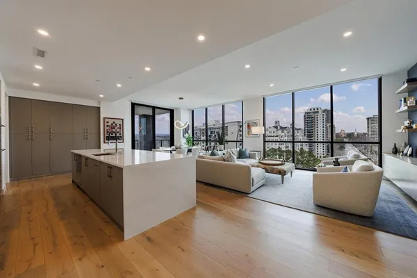a living room with couches and kitchen view with wooden floor