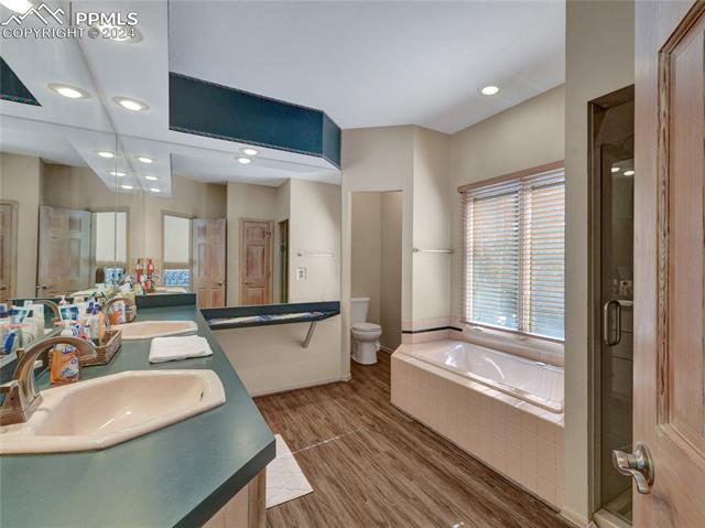4955 Dodd Road Cascade, CO 80809 - Photo 25 of 45 Full bathroom with wood-type flooring, toilet, dual bowl vanity, and separate shower and tub